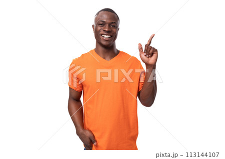 young modest handsome african man with short haircut wearing orange t-shirt smiling on white 113144107