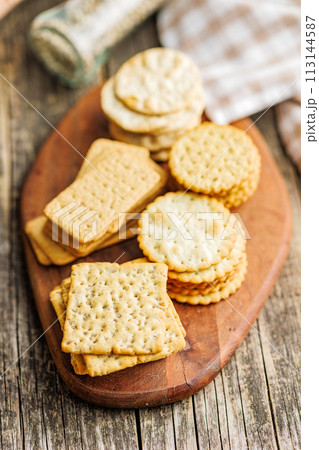 A stack of crackers neatly arranged on cutting board on wooden tabletop. A stack of crackers neatly arranged on cutting board on wooden tabletop. 113144587