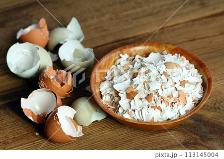 Crushed egg shells in a bowl on the wood table. Crushed egg shells in a bowl on the wood table. 113145004