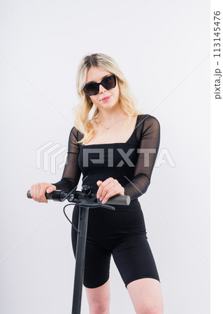 Happy young woman wear glasses riding electric scooter on background studio People lifestyle concept 113145476