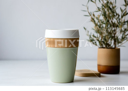 Ecological cup for coffee and tea on the table against the background of a plant in a pot 113145685
