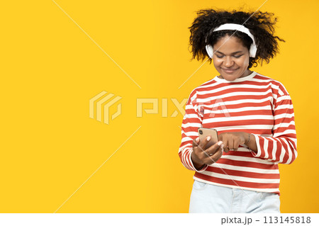 Young African American woman listening to music in headphones Young African American woman listening to music in headphones 113145818