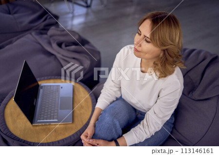 woman in casual clothes is working on a laptop on  bean bag 113146161