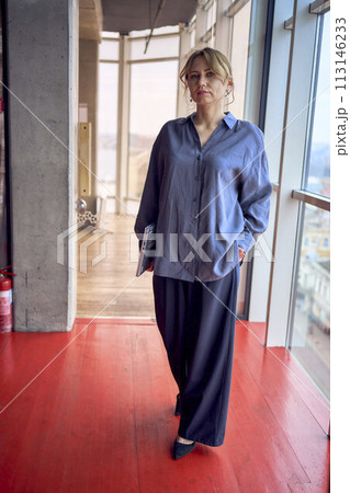 attractive middle age woman hold a laptop  in modern office near panoramic windows 113146233
