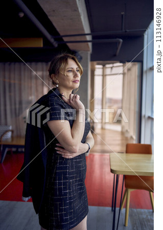 attractive woman in a black mini dress business style walks in a modern coworking space with panoramic windows and a black ceiling attractive woman in a black mini dress business style walks in a modern coworking space with panoramic windows and a black ceiling 113146928