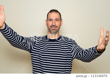 Hispanic man in his forties welcoming on a beige background Hispanic man in his forties welcoming on a beige background 113148979