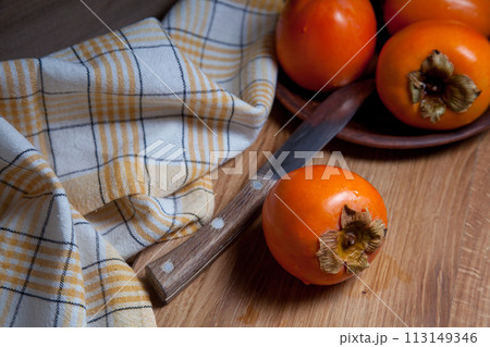 Whole ripe persimmon on a wooden background.. Whole ripe persimmon on a wooden background.. 113149346