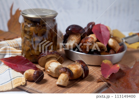 Several Imleria Badia or Boletus badius mushrooms commonly known as the bay bolete and vintage pan with mushrooms on wooden cutting board.. 113149400