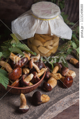 Pile of Imleria Badia or Boletus badius mushrooms commonly known as the bay bolete with canned mushroom in glass jar on vintage wooden background.. Pile of Imleria Badia or Boletus badius mushrooms commonly known as the bay bolete with canned mushroom in glass jar on vintage wooden background.. 113149680