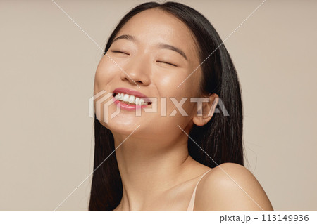 Closeup studio portrait of happy young Asian woman with long straight hair smiling with eyes closed 113149936