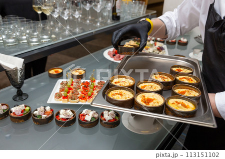 The waiter places snacks on the festive table The waiter places snacks on the festive table 113151102