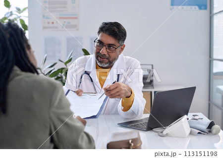 Portrait of senior bearded doctor handing clipboard to female patient across table copy space Portrait of senior bearded doctor handing clipboard to female patient across table copy space 113151198
