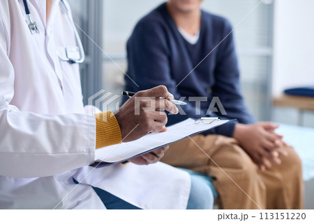 Side view closeup of Middle Eastern doctor holding clipboard while consulting child in clinic copy space 113151220