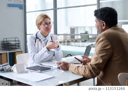 Portrait of smiling female doctor talking to patient in clinic and enjoying work copy space Portrait of smiling female doctor talking to patient in clinic and enjoying work copy space 113151268