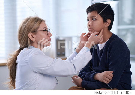 Side view portrait of female pediatrician examining young boy during health check up in clinic Side view portrait of female pediatrician examining young boy during health check up in clinic 113151306
