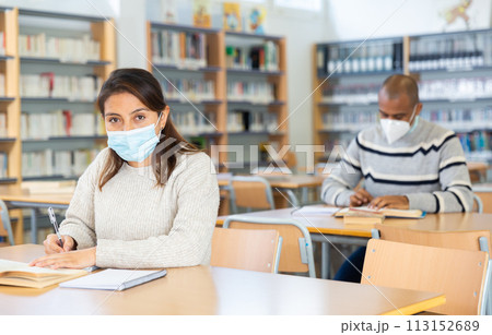 Woman wearing mask studying in public library 113152689