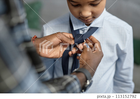 Close up of loving African American father tying tie for son first day of school 113152792