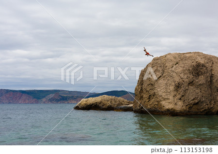 Brave Man Jumps From High Cliff Rock Into Water of Sea Brave Man Jumps From High Cliff Rock Into Water of Sea 113153198