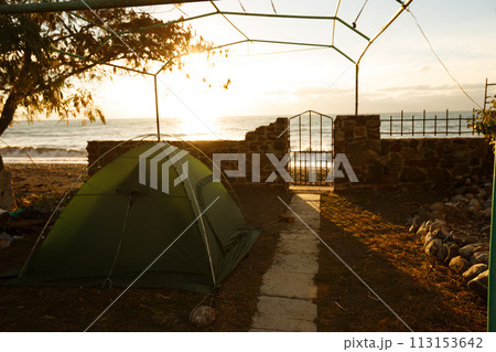 Tent on backyard near the fence and beach with sea on background in the morning sunrise Tent on backyard near the fence and beach with sea on background in the morning sunrise 113153642