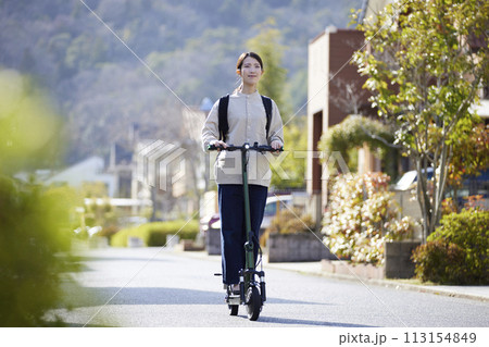 住宅街を電動キックボードで移動する日本人の女性 113154849