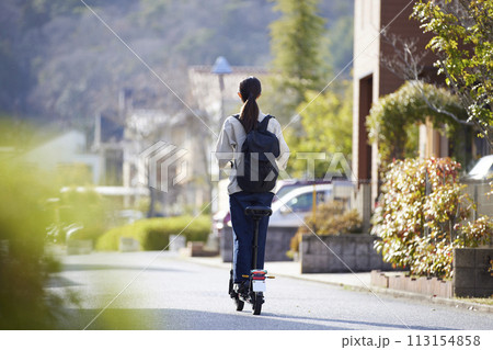 住宅街を電動キックボードで移動する日本人の女性 113154858