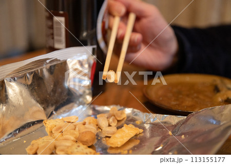 お菓子を箸で摘まんで食べる　手が汚れないように箸を使ってスナックを食べる手元 113155177