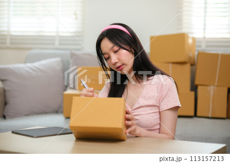 Startup small business owner working at home, woman writing address on parcel box at home for delivery order to customer, Online shopping business, ecommerce concept Startup small business owner working at home, woman writing address on parcel box at home for delivery order to customer, Online shopping business, ecommerce concept 113157213