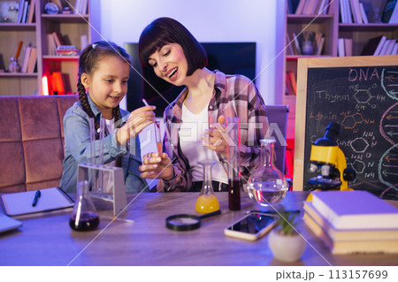 Parent mother with daughter kid making chemical test at evening time. 113157699