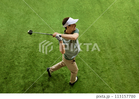 Skilled, focused on game golfer from above at end of swing posing on lush green golf court. Male model looking at distance. Skilled, focused on game golfer from above at end of swing posing on lush green golf court. Male model looking at distance. 113157780