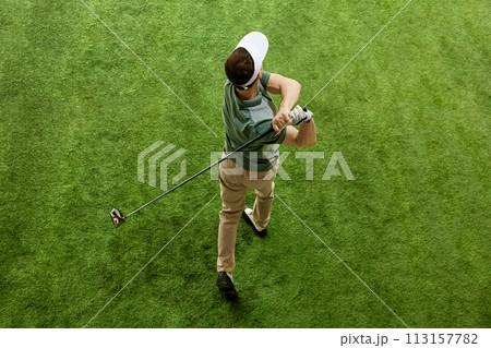 High overhead angle view of skilled golfer in casual attire hitting golf ball on fairway green grass. Concept of recreation, sport games. High overhead angle view of skilled golfer in casual attire hitting golf ball on fairway green grass. Concept of recreation, sport games. 113157782