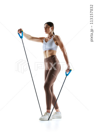 Side view photo of fitness model in activewear performing workout with stretch band against white studio background 113157832