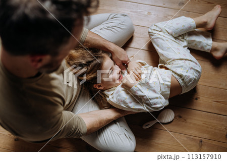 Top view of father with daughter on floor laughing together, having fun, tickling each other. Girls dad. Unconditional paternal love, Father's Day concept. 113157910