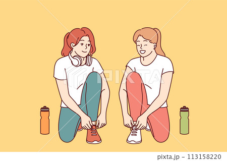 Two women runners prepare for training, tying shoelaces and discussing details of marathon Two women runners prepare for training, tying shoelaces and discussing details of marathon 113158220