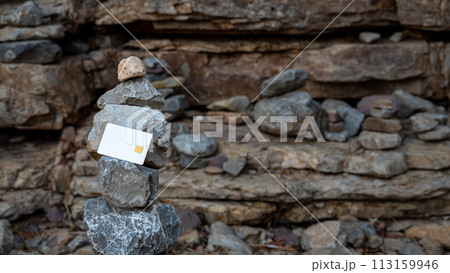 White bank card on a background of stones. The concept of bank reliability. 113159946