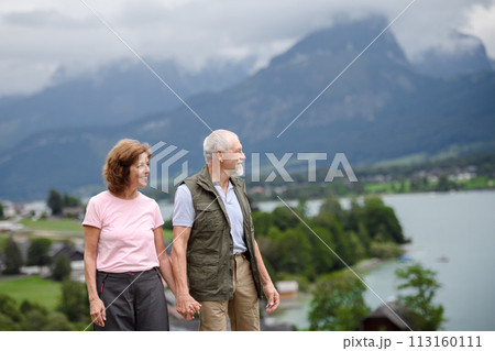 Active elderly couple hiking together in spring mountains. Senior tourists enjoying nature and exercising Active elderly couple hiking together in spring mountains. Senior tourists enjoying nature and exercising 113160111