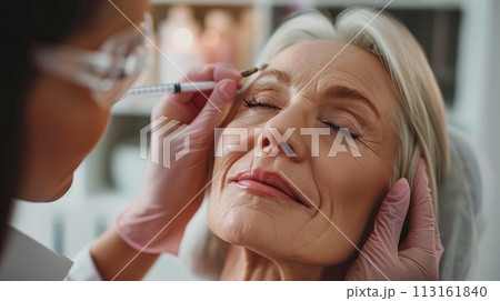 Beautiful mature woman receiving botox injection in her face at beauty salon 113161840
