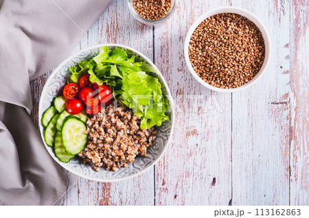 Bowl with buckwheat, cucumber, cherry tomato and lettuce for a healthy lunch top view 113162863