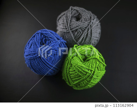 Three balls of yarn are sitting on a black background 113162904