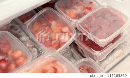 Freezer and frozen strawberries and raspberries in transparent plastic containers. Close-up Freezer and frozen strawberries and raspberries in transparent plastic containers. Close-up 113163869