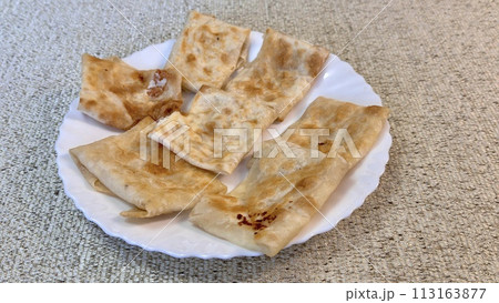 Fried pancakes-envelopes with cottage cheese, in form of envelopes in pita bread on white plate on table against background of a tablecloth 113163877