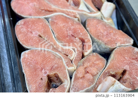 Atlantic salmon steaks from frozen raw materials on a substrate for sale in the supermarket. Close-up 113163904