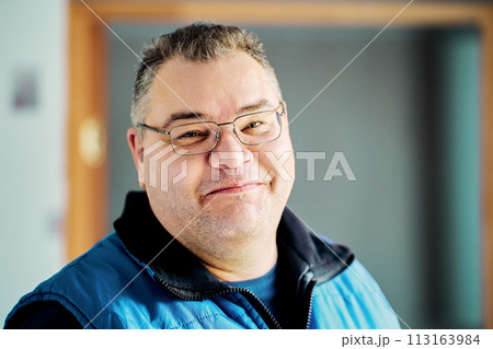 Sly smile of round faced European man over 40 wearing glasses. 113163984