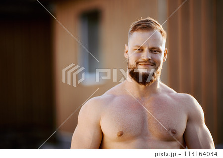 Muscular young European man without shirt outdoors in countryside near house. Muscular young European man without shirt outdoors in countryside near house. 113164034