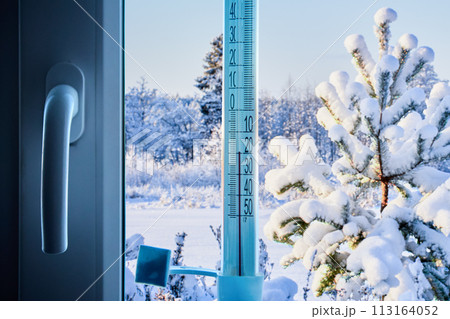 Air temperature is 20 degrees below zero Celsius on scale of an outdoor thermometer, fixed to window glass with adhesive tape on outside. 113164052