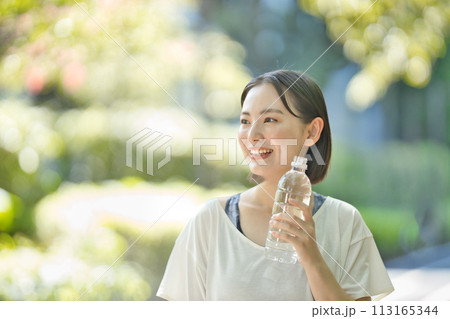 ペットボトルの水を飲むスポーツウエアの若い女性 113165344