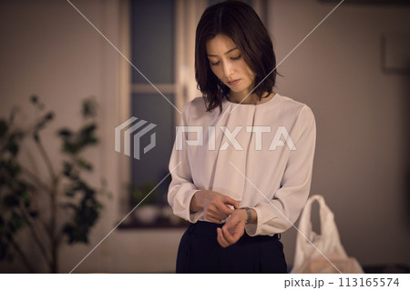 ジャケットを脱いで腕時計を外すビジネスウーマンのナイトルーティーン ジャケットを脱いで腕時計を外すビジネスウーマンのナイトルーティーン 113165574