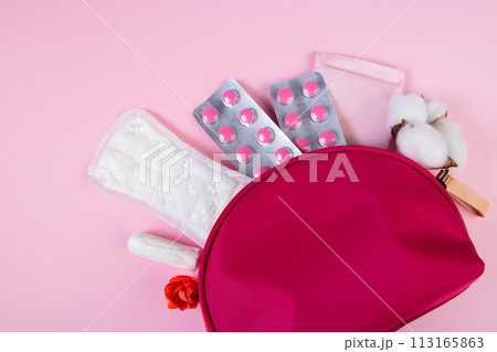 Pink cosmetic bag and set of feminine hygiene products for menstruation. Sanitary pads, tampons, pills. Womens health concept. Copy space. 113165863