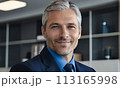 businessman, face of a blue-eyed gray-haired man, business concept, man smiling, head office employee, friendly employer, businessman sitting at his desk, gray-haired handsome man in a jacket smiling 113165998