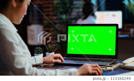 Worker looks over statistical financial data on chroma key laptop, researching data for company project. Businesswoman analyzing stock market figures and charts on mockup device Worker looks over statistical financial data on chroma key laptop, researching data for company project. Businesswoman analyzing stock market figures and charts on mockup device 113168249