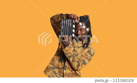 Male model posing with clapperboard in front of camera, using movie production instrument to cut scenes and say action. African american film director and producer holding flap board. Male model posing with clapperboard in front of camera, using movie production instrument to cut scenes and say action. African american film director and producer holding flap board. 113168329